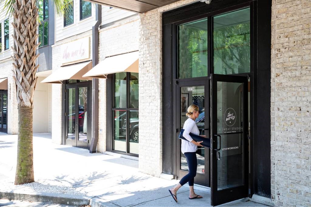 A woman is walking out of a building with a glass door.