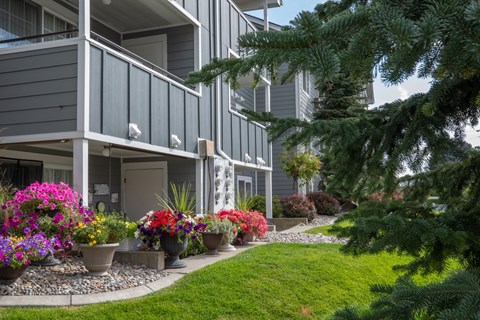 A grey building with a balcony and a garden in front of Morning Glory Circle Apartments, 99208