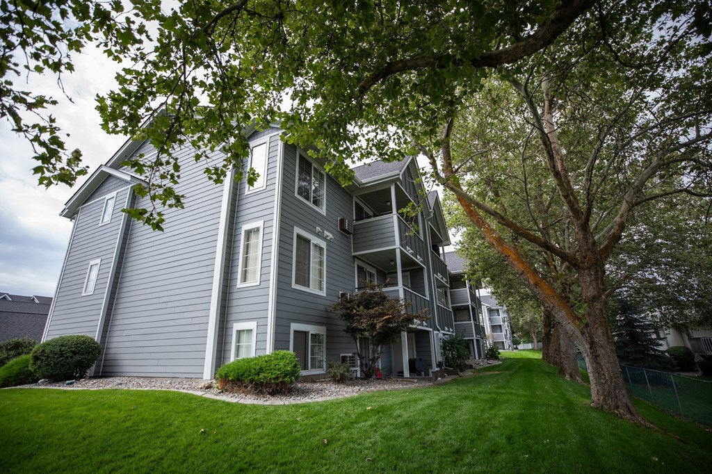 A grey apartment building with a tree at Morning Glory Circle Apartments, Washington, 99208
