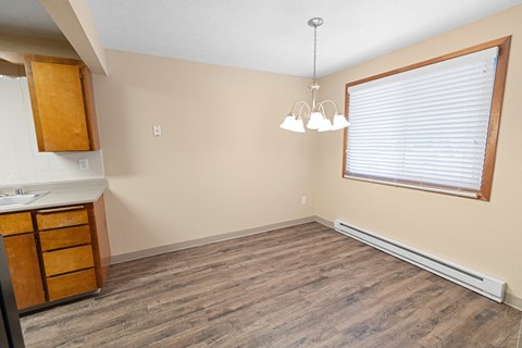 A kitchen with wooden cabinets and a window with blinds.