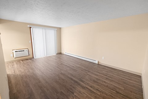 A room with wooden flooring and a window with blinds.