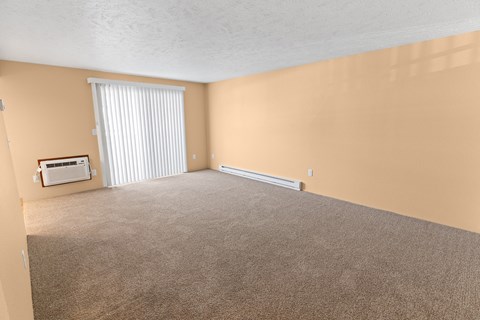 A room with a carpeted floor and a window with blinds.
