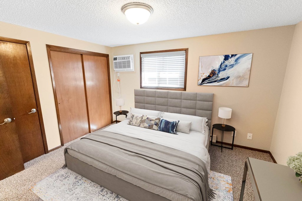 A bedroom with a bed, nightstand, and a painting on the wall.