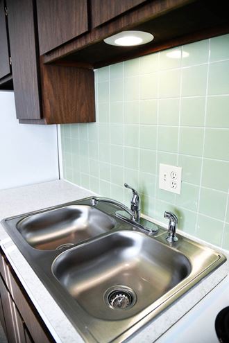 a kitchen sink with green tile behind it