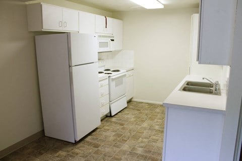 a kitchen with white appliances and a sink and refrigerator