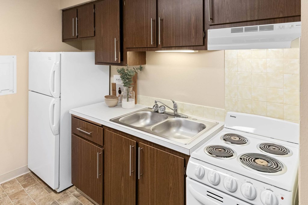 A kitchen with a white fridge, white stove, and brown cabinets.