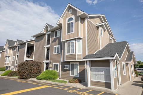 A large, multi-story residential building with a parking lot in front.