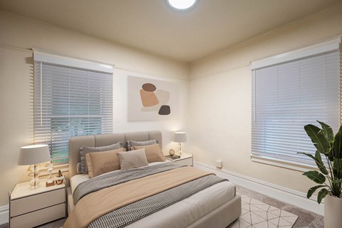 A well-lit bedroom with a large bed and a nightstand with a lamp.