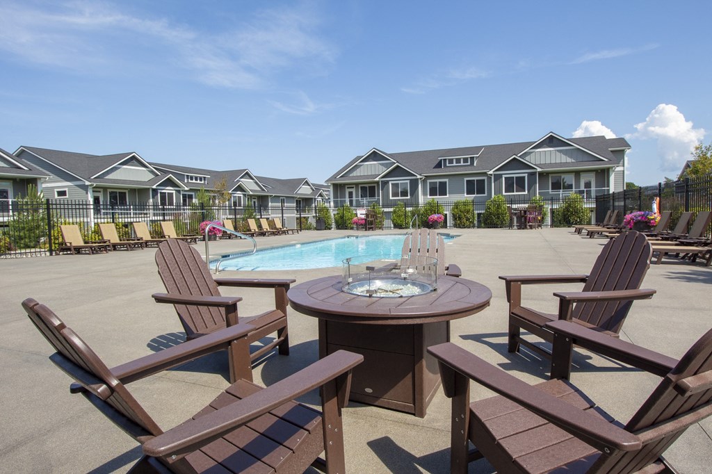 a patio with a table and chairs next to a pool with houses in the background