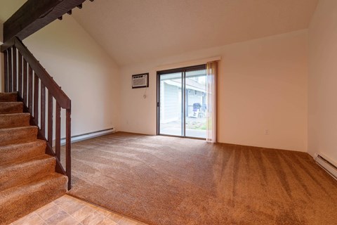 a living room with a staircase and a sliding glass door