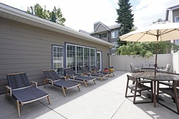 A patio with a table, chairs and an umbrella at Graymayre Crossing Apartments, Spokane, WA, 99208