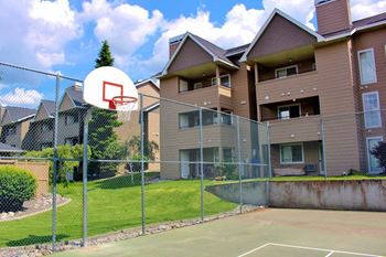 A basketball hoop is mounted on a chain link fence in front of apartment buildings at Graymayre Crossing Apartments, Spokane, WA