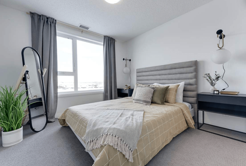 A bedroom with a large bed and a window with curtains.