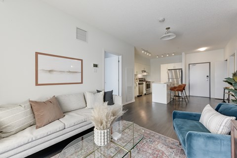 A living room with a white couch and a glass coffee table.
