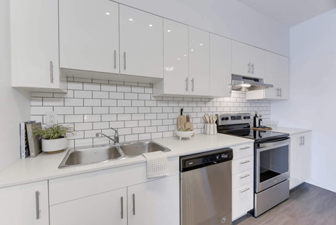 A modern kitchen with white cabinets and stainless steel appliances.