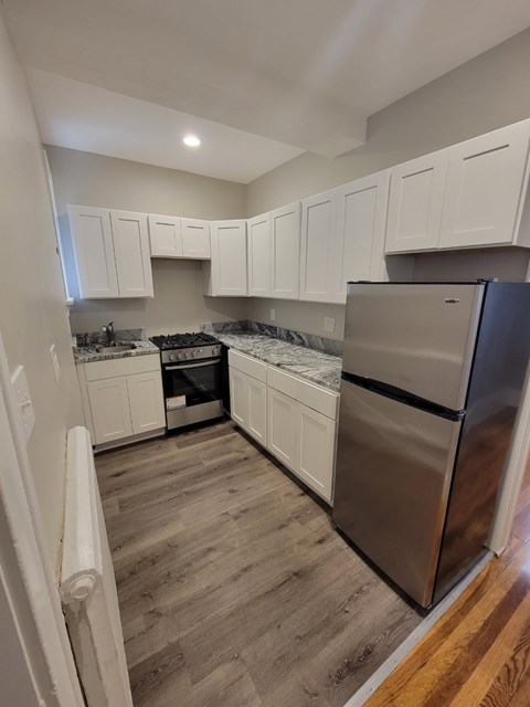 A kitchen with white cabinets and a stainless steel refrigerator.