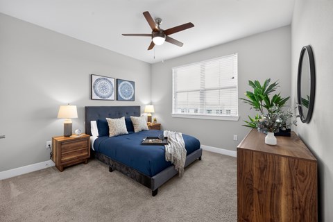 A bedroom with a bed, nightstand, and a ceiling fan.