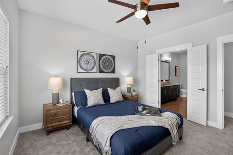 A bedroom with a bed, nightstands, and a ceiling fan.