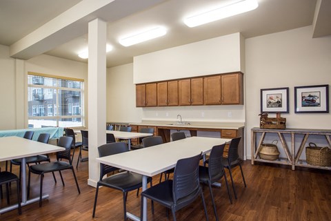 A kitchen with a table and chairs in the foreground and a counter with cabinets in the background.