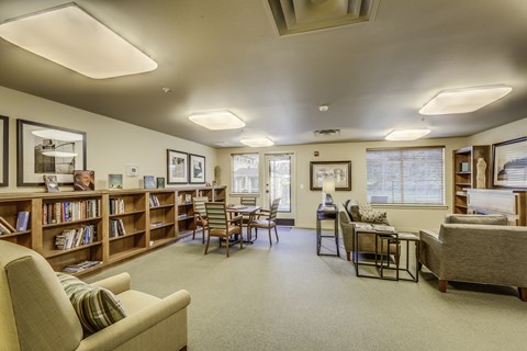 A cozy living room with a bookshelf, couch, and chairs.