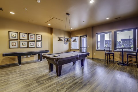 A room with a pool table and a bar area.