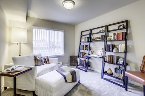 A cozy bedroom with a bed, a table, and a bookshelf.