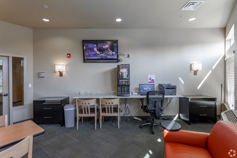 A conference room with a television mounted on the wall and a desk with a computer.
