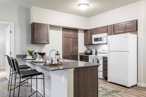 A kitchen with white appliances and brown cabinets.