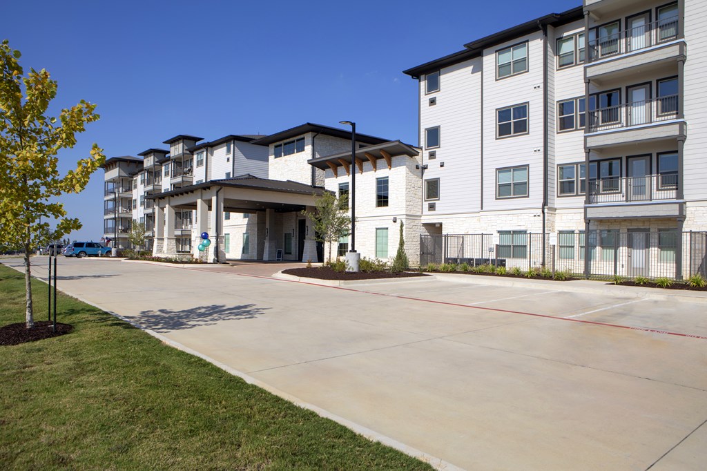 Apartment complex with a tree on the left and a clear blue sky.