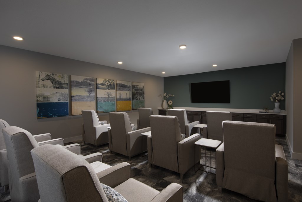 A living room with a grey couch and a painting on the wall.