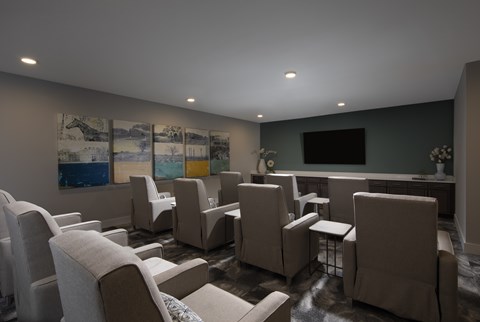 A living room with a grey couch and a painting on the wall.