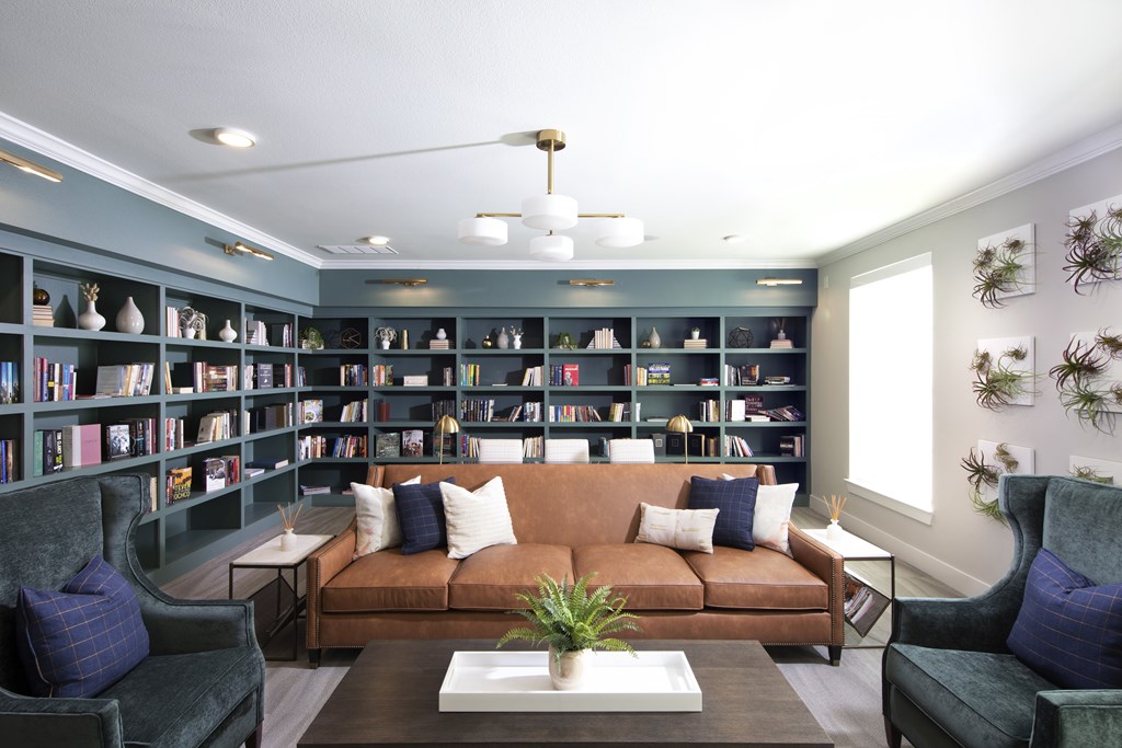 A living room with a brown couch, a coffee table, and a bookshelf filled with books.