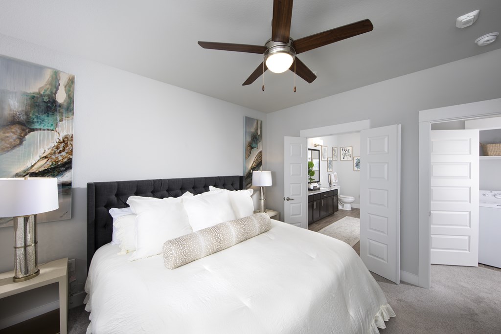 A bedroom with a large bed and a ceiling fan.