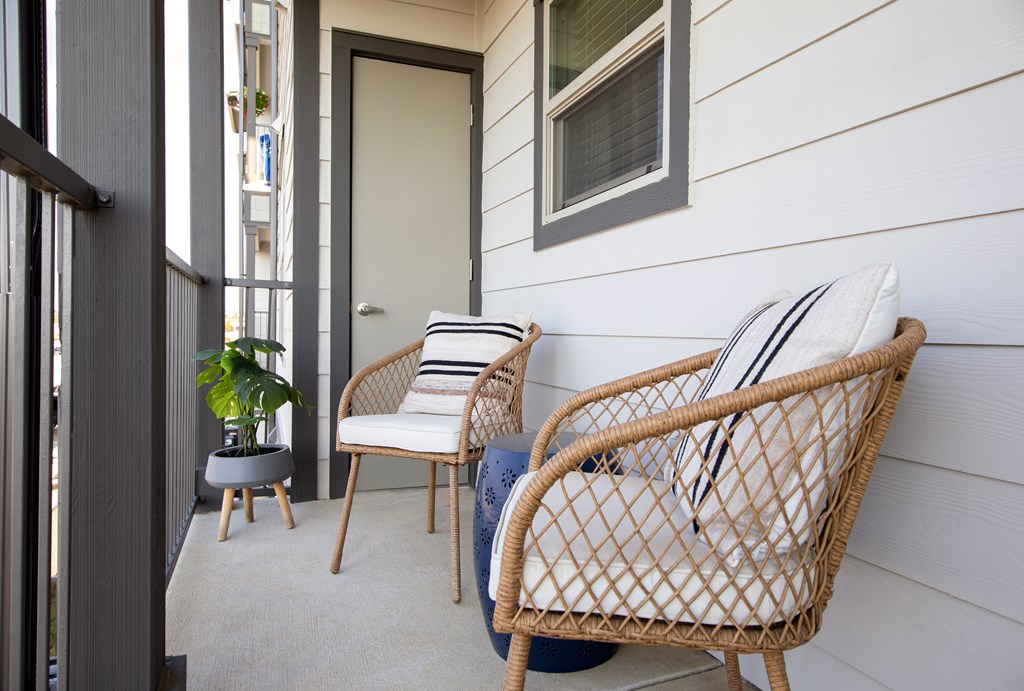 A chair with a white cushion and a blue cushion is on a porch.