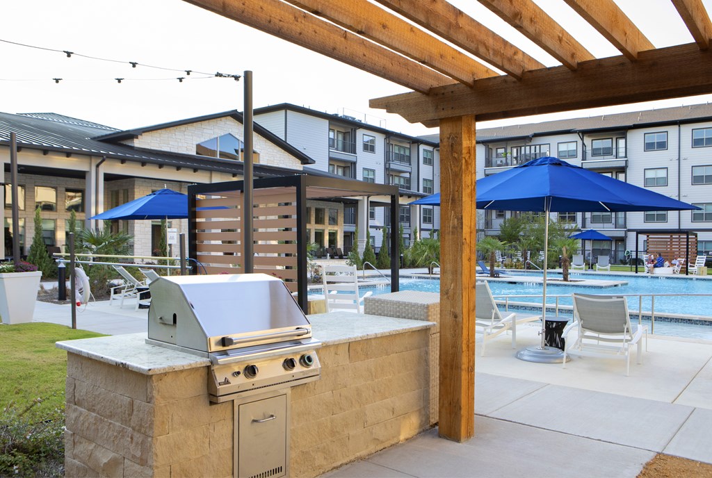 A barbecue grill is set up on a patio next to a swimming pool.