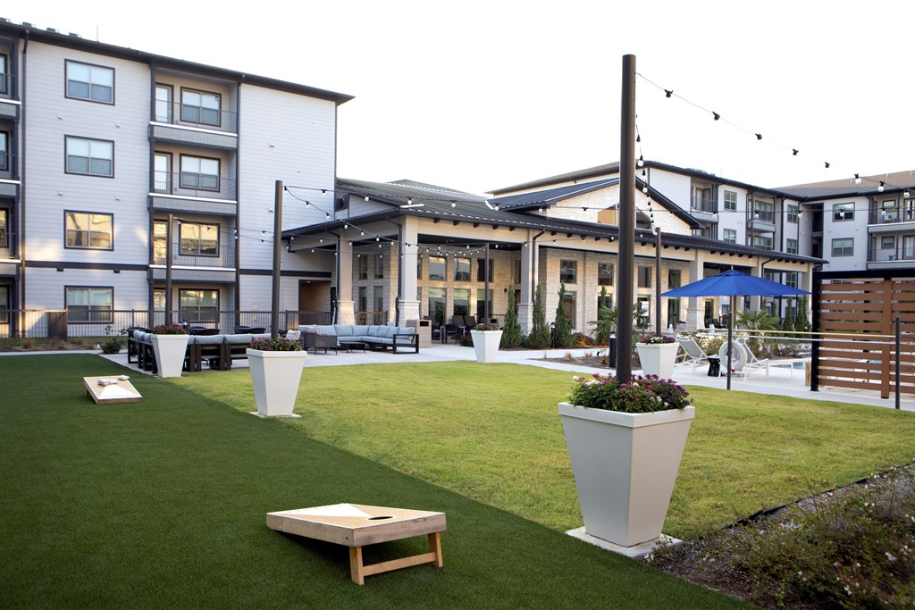 A grassy area with a bench and a planter in the foreground with apartment buildings in the background.