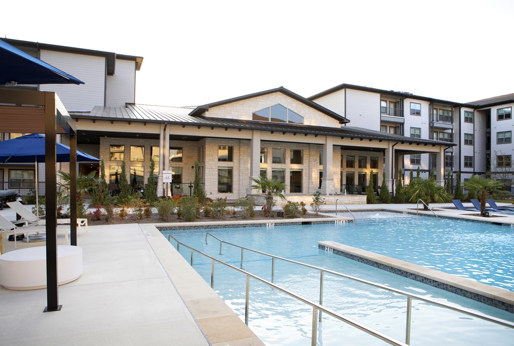 A swimming pool is surrounded by a metal fence and a building.