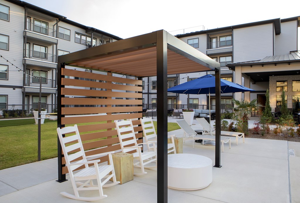 A wooden bench with a canopy is in the foreground of a courtyard.