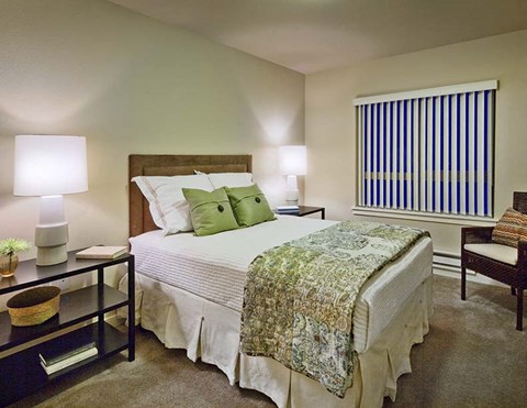 A bedroom with a bed, nightstand, and window.