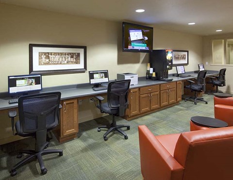 A conference room with a long table and chairs, a television on the wall, and a framed picture.