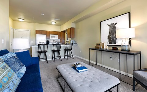 A living room with a grey sofa and a painting of a horse on the wall.