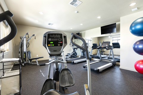 A gym with a treadmill, elliptical machines, and other exercise equipment.