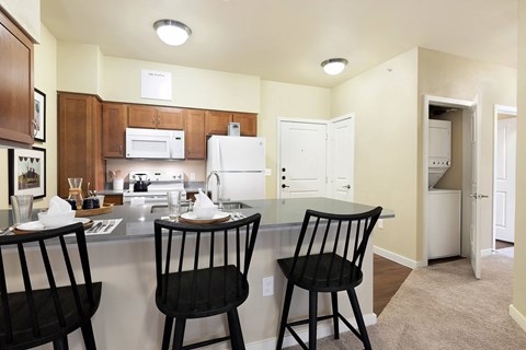 A kitchen with a white refrigerator, brown cabinets, and a table with three chairs.