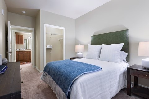 A bedroom with a bed, nightstand, and a mirror.