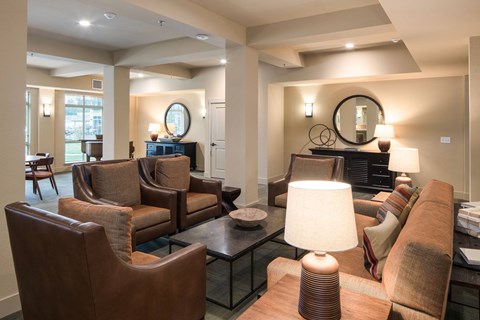 A living room with brown leather furniture and a glass coffee table.