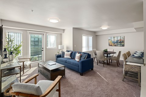A living room with a blue couch and a brown chair.