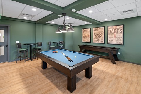 A pool table is in the middle of a room with green walls.