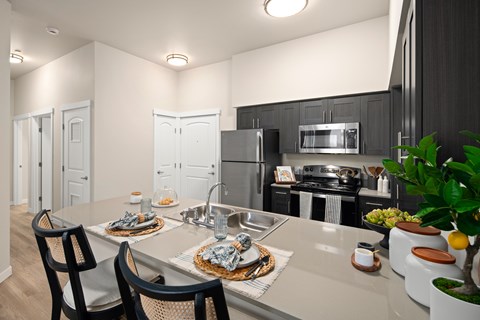 A modern kitchen with a dining table set for two.