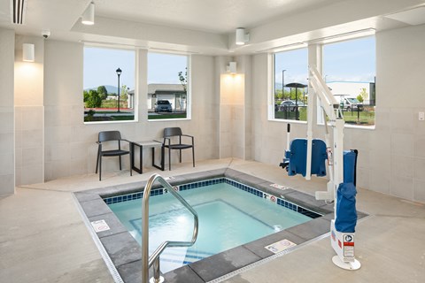 A small indoor pool with a ladder and a few chairs.