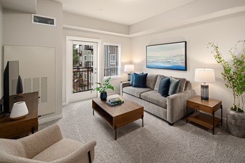 A living room with a grey couch, a coffee table, a chair, and a painting on the wall.